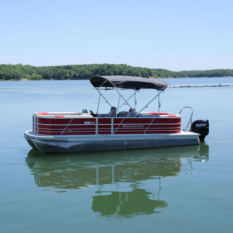 The Image of 2024 Berkshire 24RFX LE pontoon boat on a serene lake with lush green shoreline. - 0