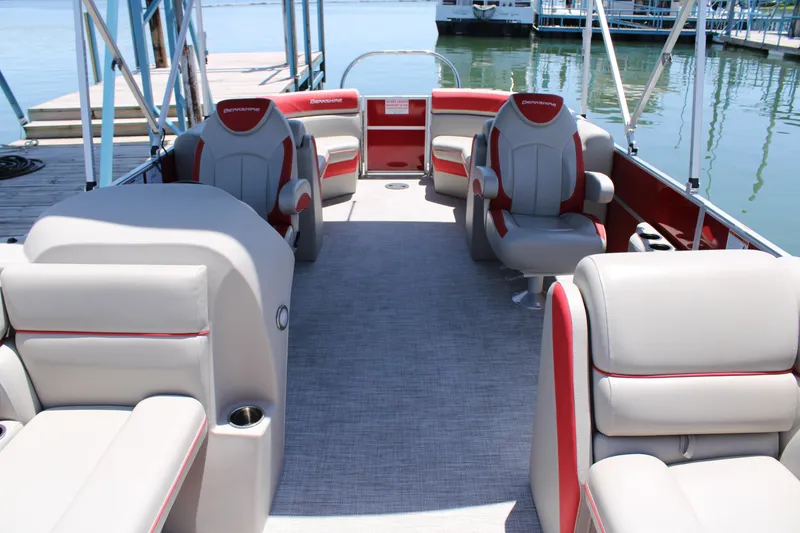Slide: The Image of 2024 Berkshire 24RFX LE pontoon boat interior with gray and red seating, docked by the water. - 4