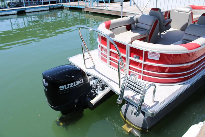 Slide: The Image of 2024 Berkshire 24RFX LE pontoon boat with Suzuki outboard motor, docked on calm water. - 8