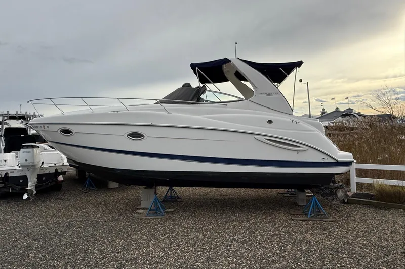 The Image of 2004 Maxum 3100 SE boat on stands, displayed outdoors on gravel. - 0