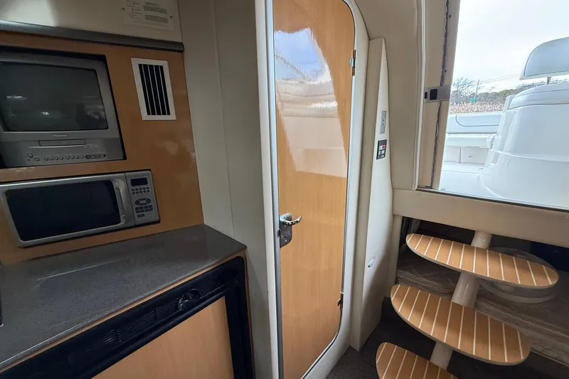 Slide: The Image of Interior of 2004 Maxum 3100 SE boat with TV, microwave, and wooden steps. - 17
