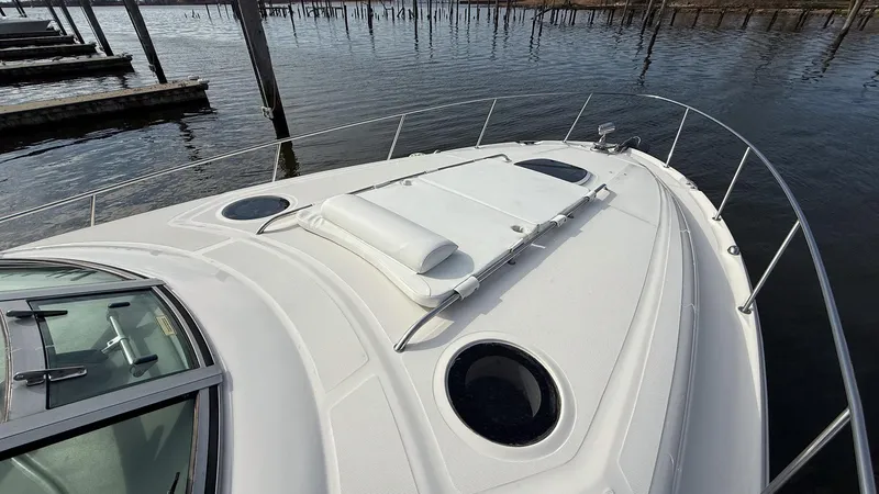 Slide: The Image of 2008 Sea Ray 340 Sundancer boat deck with sunpad and portholes, docked by the water. - 18