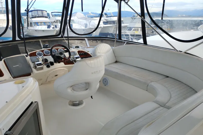 Slide: The Image of 2004 Meridian 459 Motoryacht helm with white seating and panoramic marina view. - 12