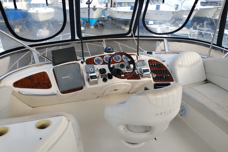 Slide: The Image of 2004 Meridian 459 Motoryacht helm with luxurious white seating and advanced navigation controls. - 14