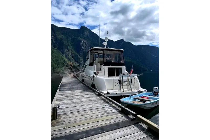 Slide: The Image of 2004 Meridian 459 Motoryacht docked by scenic mountains and cloudy sky. - 2