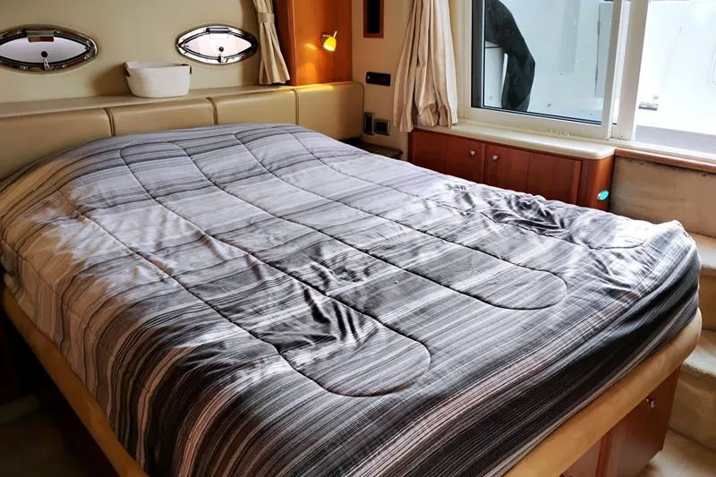 Slide: The Image of Luxurious bedroom interior of 2004 Meridian 459 Motoryacht with striped bedding and porthole windows. - 35