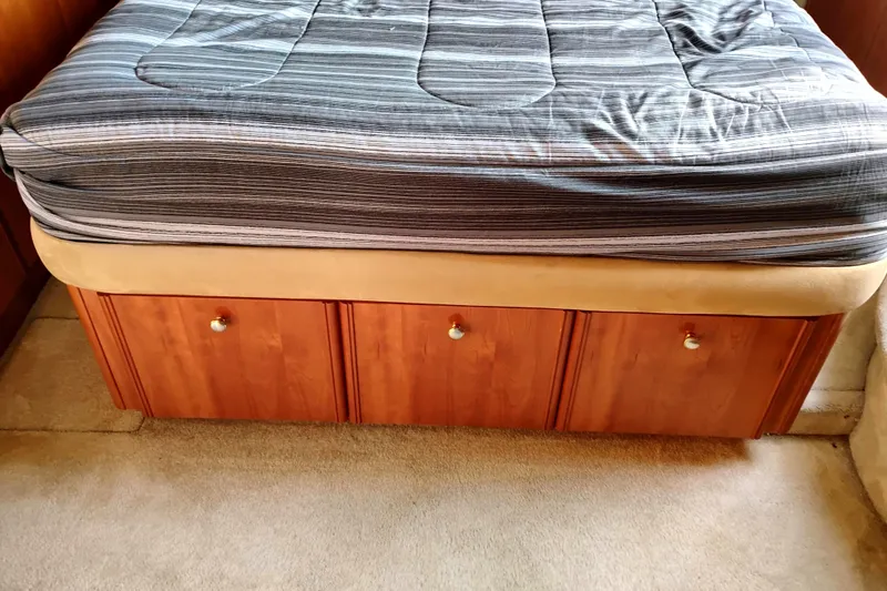 Slide: The Image of Bed with striped bedding and wooden storage drawers in 2004 Meridian 459 Motoryacht. - 36