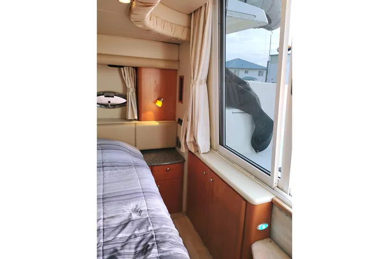 Slide: The Image of 2004 Meridian 459 Motoryacht interior cabin with bed, window, and wooden cabinetry. - 37