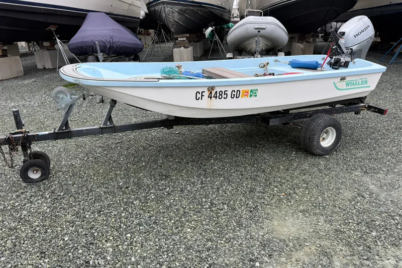 Slide: The Image of Small Boston Whaler boat on trailer with Honda outboard motor, parked on gravel. - 88