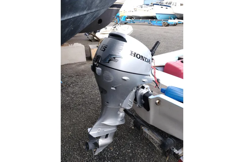Slide: The Image of Silver Honda outboard motor attached to a boat, with other boats in the background. - 89