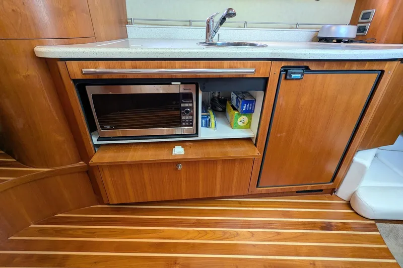 Slide: The Image of 2008 Tiara Yachts 3600 Sovran galley with microwave, sink, and wooden cabinetry. - 35