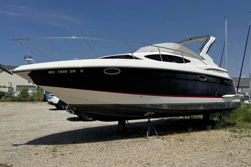 Slide: The Image of 2004 Regal 3060 Window Express boat on dry land, black and white hull, sunny day. - 5