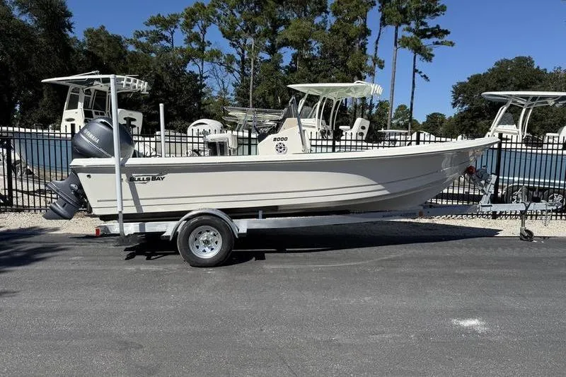 Slide: The Image of 2026 Bulls Bay 2000 boat on trailer, parked outdoors with trees in background. - 1
