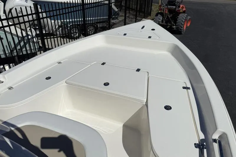 Slide: The Image of 2026 Bulls Bay 2000 boat deck with storage compartments, parked near a fence. - 5
