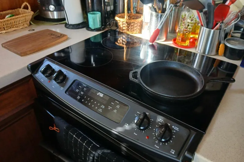 Slide: The Image of Modern kitchen stove with cast iron skillet, surrounded by utensils and cutting board. - 15