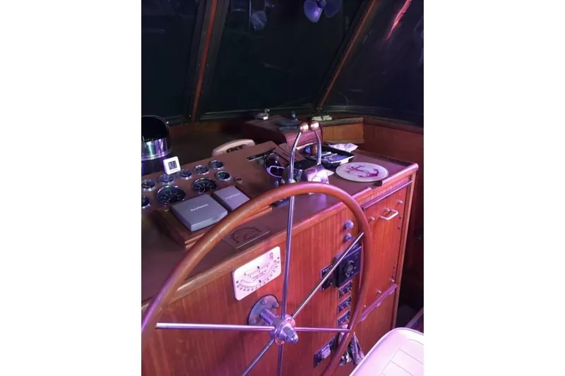 Slide: The Image of 1977 Hatteras 48 Long Range Cruiser helm with gauges and wooden steering wheel. - 23