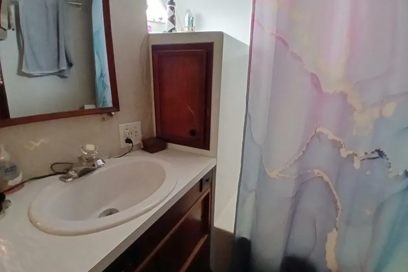 Slide: The Image of Bathroom interior of 1977 Hatteras 48 Long Range Cruiser with sink and colorful shower curtain. - 36