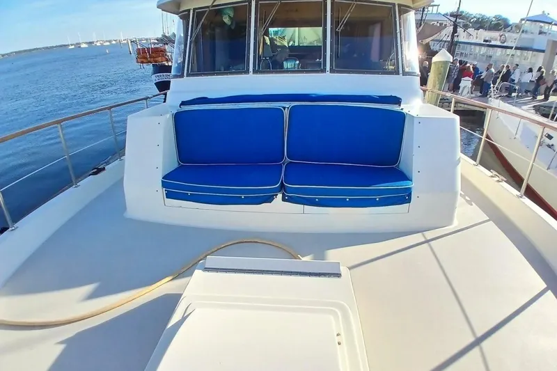 Slide: The Image of 1977 Hatteras 48 Long Range Cruiser with blue seating on deck, docked by the water. - 52