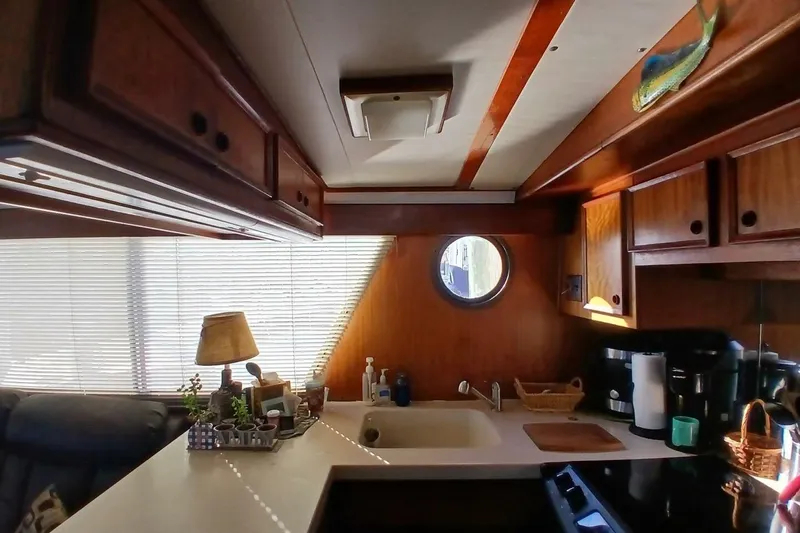 Slide: The Image of Interior of 1977 Hatteras 48 Long Range Cruiser kitchen with wooden cabinets and porthole window. - 8
