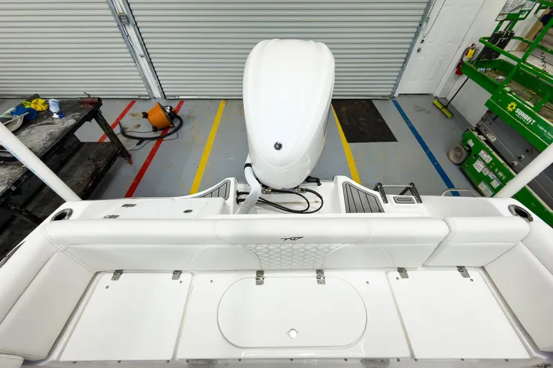 Slide: The Image of 2026 Tidewater 232 LXF boat interior with white seating and engine in a garage. - 12