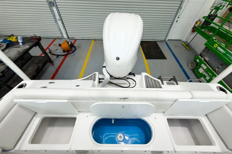 Slide: The Image of 2026 Tidewater 232 LXF boat interior with storage compartments and motor in a garage. - 13