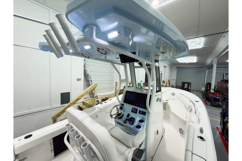 Slide: The Image of 2026 Tidewater 232 LXF boat interior with modern helm and seating in a garage. - 16