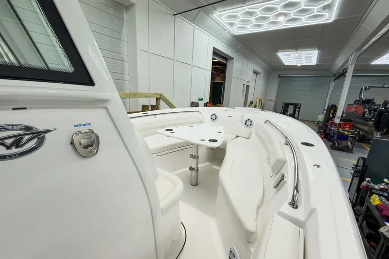 Slide: The Image of 2026 Tidewater 232 LXF boat interior with seating and table in a showroom. - 32