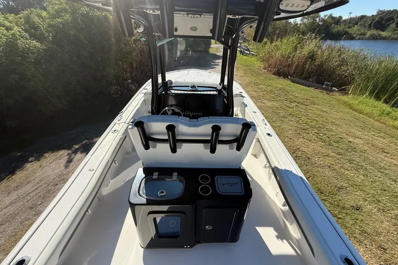 Slide: The Image of 2021 Tidewater 2700 Carolina Bay boat interior with console and seating, near a grassy shoreline. - 14