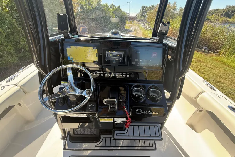 Slide: The Image of 2021 Tidewater 2700 Carolina Bay boat dashboard with navigation screens and steering wheel. - 16