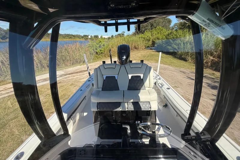 Slide: The Image of 2021 Tidewater 2700 Carolina Bay boat interior with seating and steering wheel, near a lake. - 23