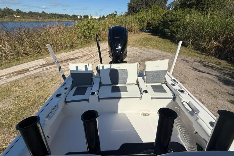 Slide: The Image of 2021 Tidewater 2700 Carolina Bay boat interior with seating and motor, near a lake. - 26