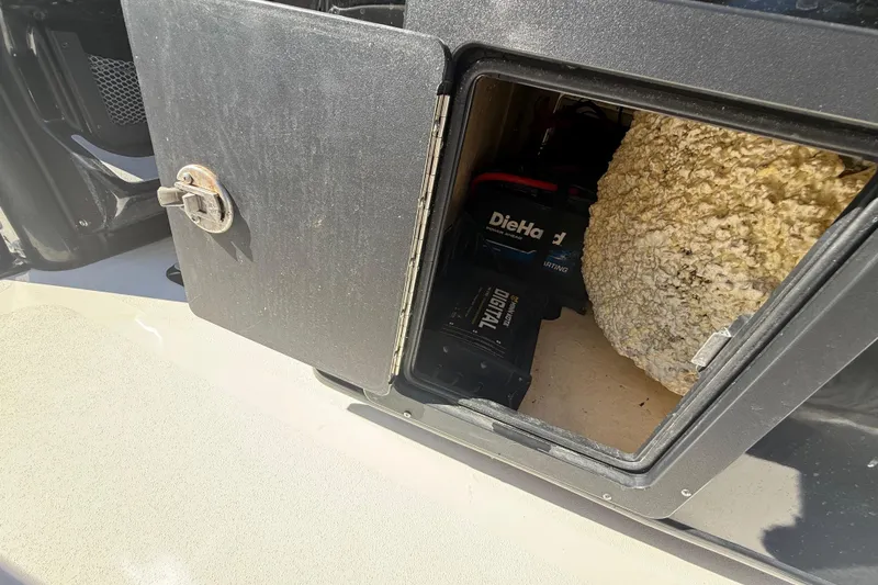 Slide: The Image of Open storage compartment on 2021 Tidewater 2700 Carolina Bay boat, showing DieHard battery inside. - 38