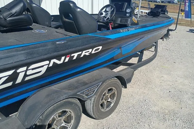 Slide: The Image of 2022 Tracker Nitro Z19 boat on trailer, blue and black design, parked outdoors. - 5