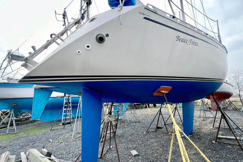 Slide: The Image of 1981 Beneteau First 32 sailboat on stands, hull painted blue, named "Beaux-Frères." - 2