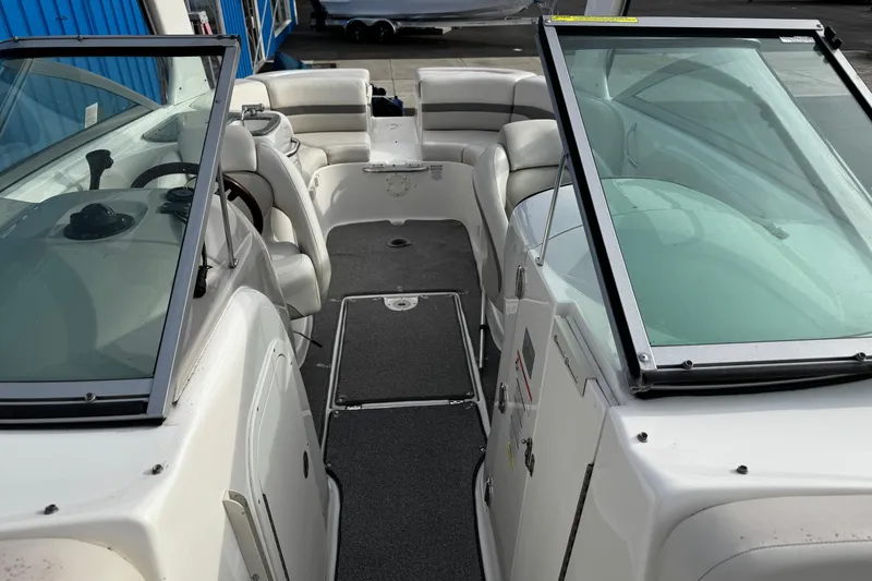 Slide: The Image of 2008 Chaparral 256 SSi boat interior with seating and windshield, docked near blue building. - 33