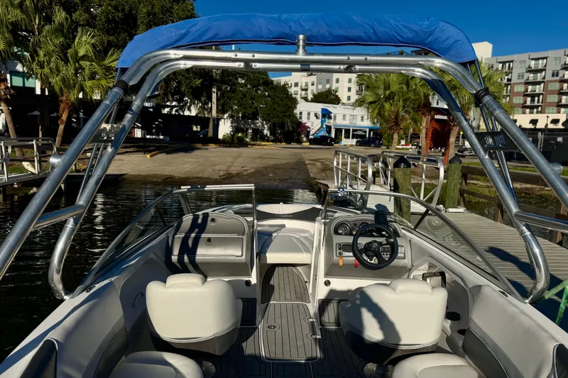 Slide: The Image of 2005 Yamaha Boats SX230 interior with seating and steering, docked near palm trees and buildings. - 15