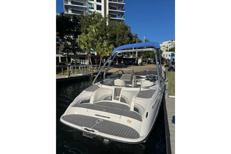 Slide: The Image of 2005 Yamaha Boats SX230 docked near modern buildings, featuring sleek design and blue canopy. - 18