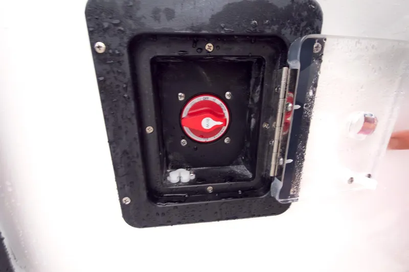 Slide: The Image of Battery switch on 2026 Tidewater 210 LXF boat, wet surface, protective cover open. - 27