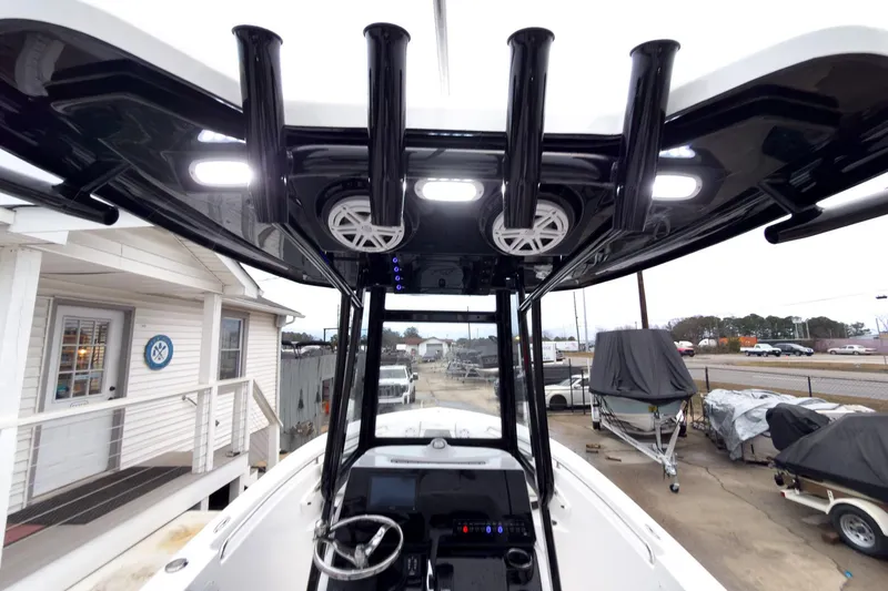 Slide: The Image of 2026 Tidewater 210 LXF boat interior with T-top, rod holders, and speakers. - 8