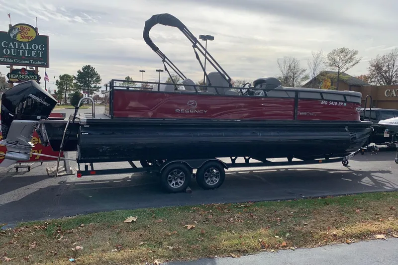 The Image of 2024 Regency 250DL3 pontoon boat on trailer at outdoor retail location. - 1