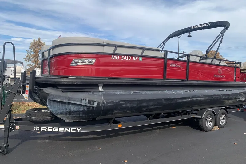 Slide: The Image of 2024 Regency 250DL3 pontoon boat on trailer, red exterior, parked outdoors. - 6