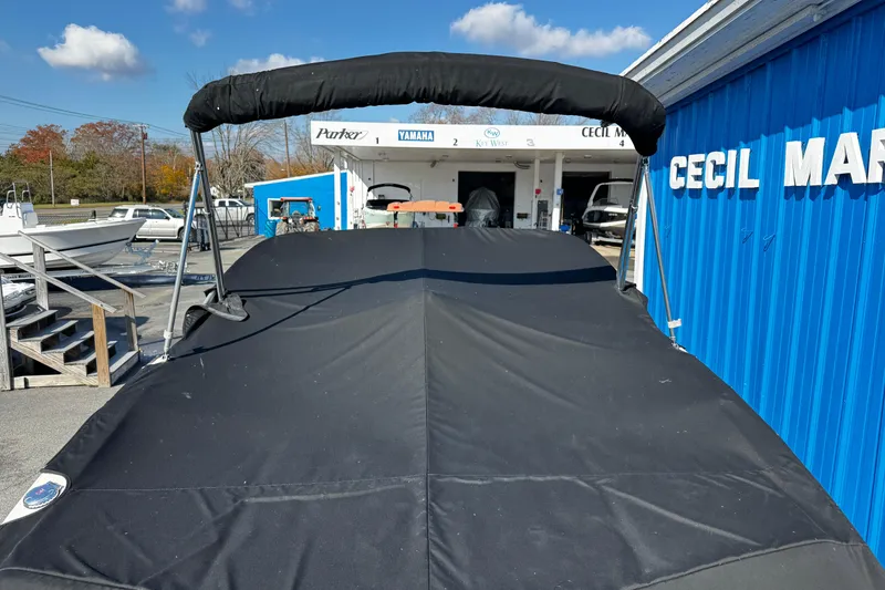 Slide: The Image of 2016 Chaparral 21 H2O Sport boat with cover at marina, blue building background. - 8