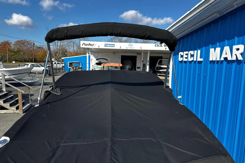 Slide: The Image of 2016 Chaparral 21 H2O Sport boat with cover at marina, blue building background. - 9