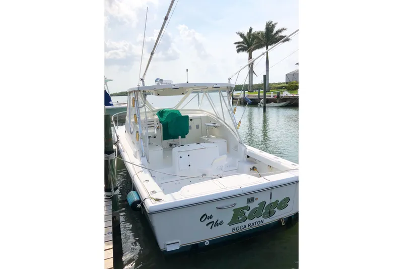 Slide: The Image of 2001 Pursuit 3000 Offshore boat docked, featuring spacious deck and palm trees in background. - 3