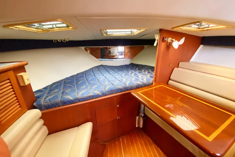 Slide: The Image of 2001 Pursuit 3000 Offshore cabin interior with bed, table, and seating. - 34