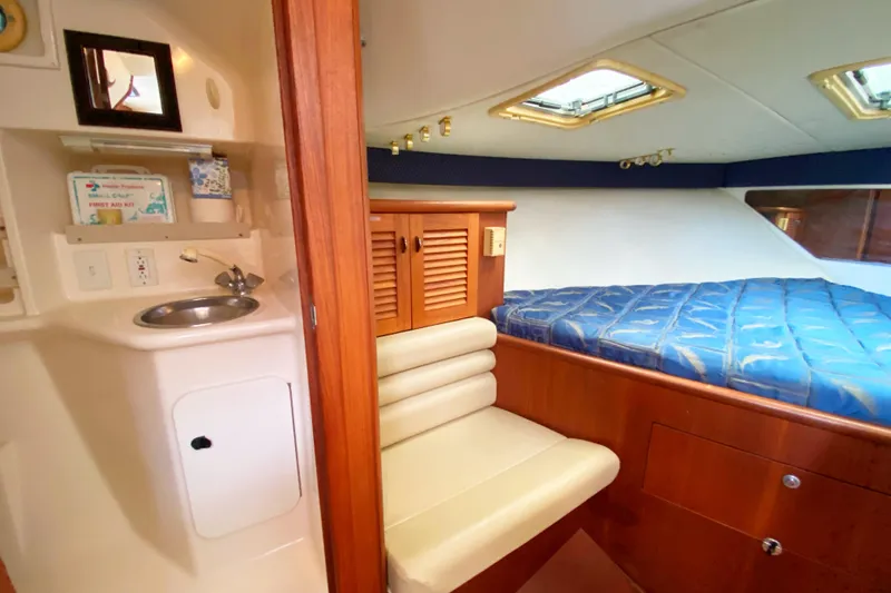 Slide: The Image of 2001 Pursuit 3000 Offshore cabin with bed, sink, and seating area. - 36