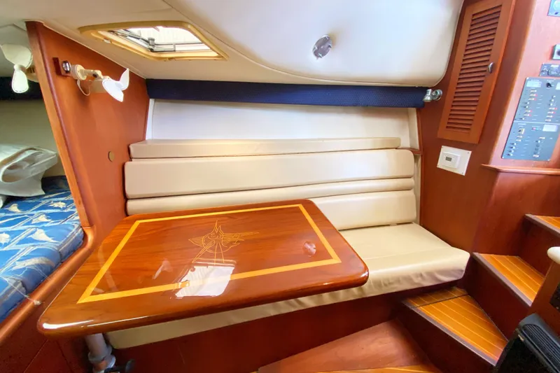 Slide: The Image of 2001 Pursuit 3000 Offshore cabin with wooden table and cushioned seating. - 38