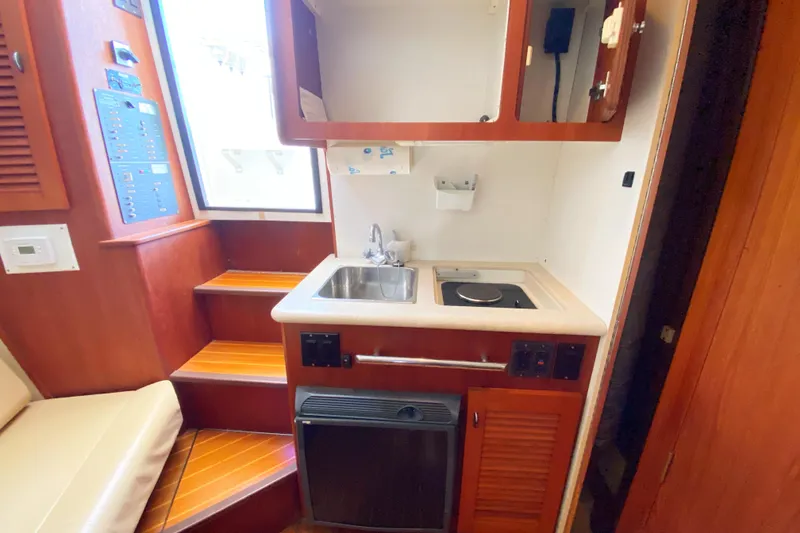 Slide: The Image of Compact kitchen area in a 2001 Pursuit 3000 Offshore boat, featuring sink and stove. - 42