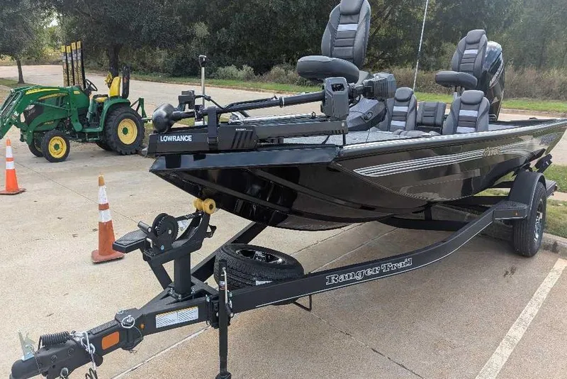 Slide: The Image of 2026 Ranger RT178C fishing boat on trailer, parked near green tractor. - 3