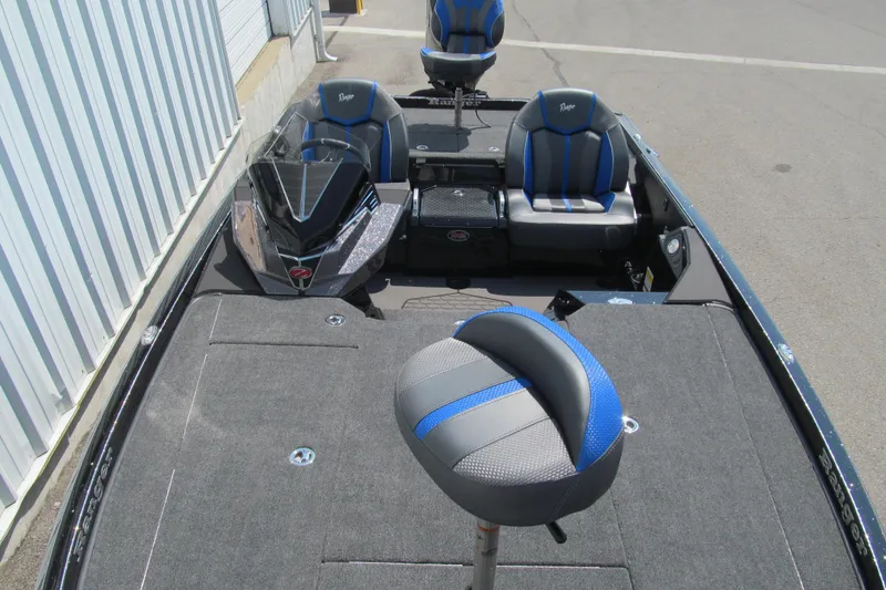 Slide: The Image of 2026 Ranger Z520 boat interior with blue and gray seating, docked near a building. - 9